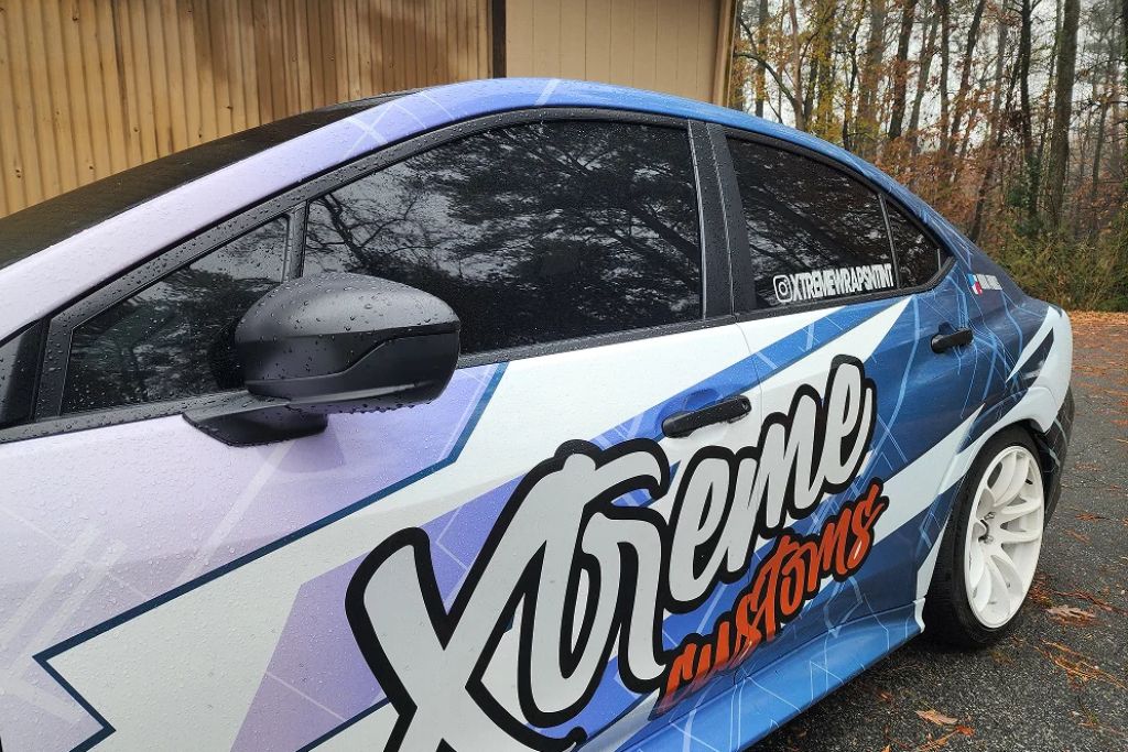 Custom wrapped sedan with Xtreme Customs branding and tinted side windows